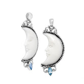 Crescent moon face pendant in sterling silver with carved bone and sparkling blue topaz accent, handmade in Bali.